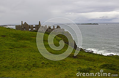 The shadowy ruins of the medieval Irish Dunluce Castle on the cliff top overlooking the Atlantic Ocean in Ireland Stock Photo