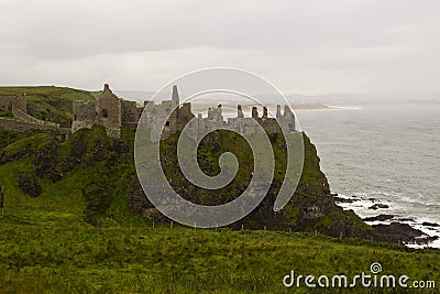 The shadowy ruins of the medieval Irish Dunluce Castle on the cliff top overlooking the Atlantic Ocean in Ireland Stock Photo