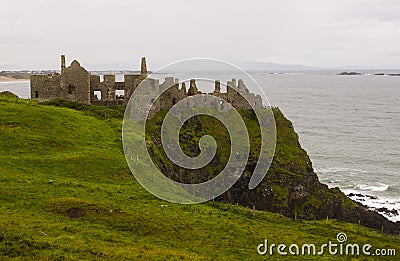 The shadowy ruins of the medieval Irish Dunluce Castle on the cliff top overlooking the Atlantic Ocean in Ireland Stock Photo