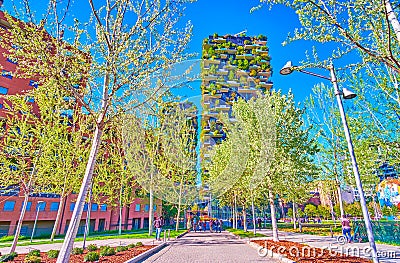 The shady alley of Biblioteca degli Alberi Park with bosco Verticale buildings on background, Milan, Italy Editorial Stock Photo