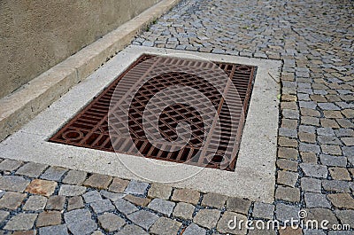 Shady corner behind the house by a road of granite cubes. metal ventilation grilles in the tiles resemble a carpet or doormat. whi Stock Photo