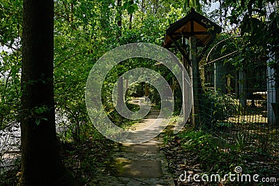 Shady riverside path before fenced farmhouse in sunny summer Stock Photo