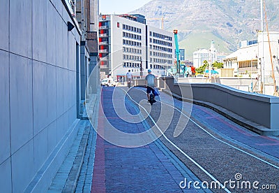 Shady side road leading to Silo District at the Waterfront. Men riding electric unicycles in foreground. Editorial Stock Photo