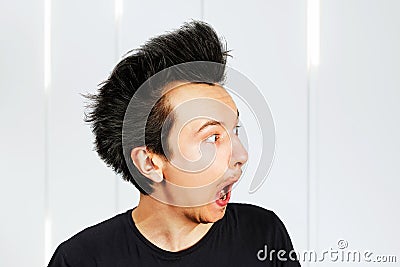 Shaggy young man with long hair surprised with open mouth on a white background Stock Photo