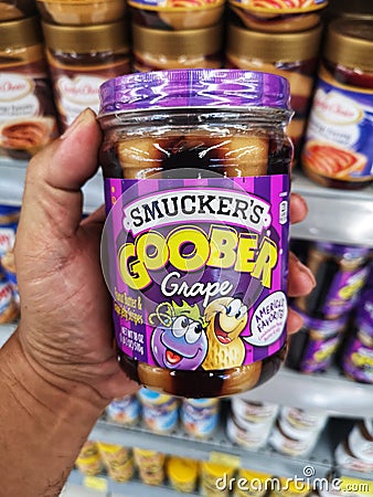 SHAH ALAM, MALAYSIA - 8 October 2020 : Hand hold a jar of SMUCKERS Goober Grape peanut butter for sell in the supermarket. Editorial Stock Photo