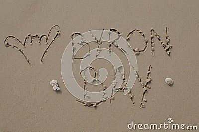 Shaka hand gesture and Byron Bay inscription in the sand Stock Photo