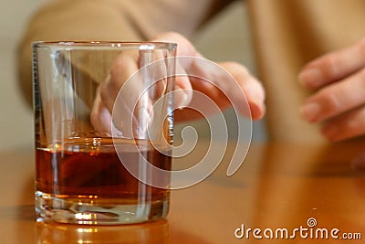 Shaking woman hand reaching of glass with whiskey standing on a wooden table, woman`s alcoholism problem Stock Photo