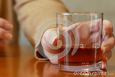 Shaking woman hand reaching of glass with whiskey standing on a wooden table, woman`s alcoholism problem Stock Photo