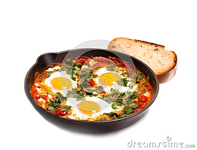 Shakshuka with Spinach and Harissa in a frying pan on white background. Colorful breakfast.Traditional cuisine of Israel Stock Photo