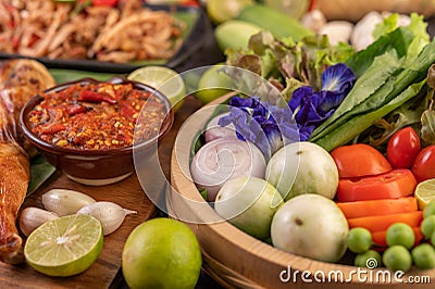 Shallots, eggplants, tomatoes, lemons, garlic, Butterfly pea flowers, chili paste and grilled chicken on wood Stock Photo