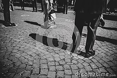 Shallow depth of field selective focus details with feet of people standing on special spots for social distancing at an event, Stock Photo