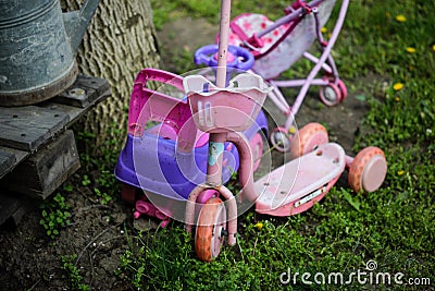 Shallow depth of field selective focus details with old and dirty small girl toys scooter, baby stroller Stock Photo