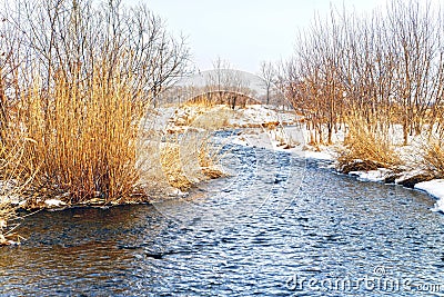Shallow, fast, unfrozen river in winter. Snow melts spring streams. HDR Stock Photo