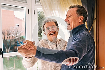 Shallow focus of a cheerful adult couple laughing and dancing in a house Stock Photo