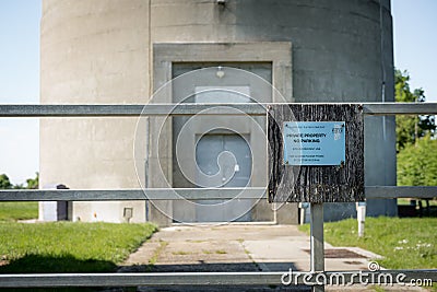 Shallow focus of a water supply company gated entrance, showing part of the large concrete water tower. Editorial Stock Photo