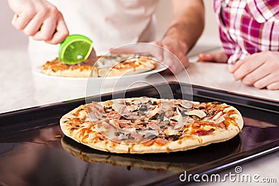 Shallow focus closeup shot of people cutting delicious homemade pizza Stock Photo