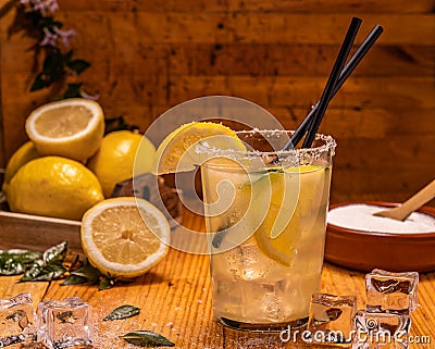 Shallow focus shot of a glass of lemonade with ice cubes, plastic straws, lemon slices, and sugar Stock Photo