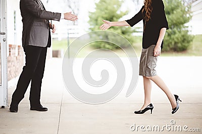 Shallow focus shot of a male and a female reaching to each other to shake hands by a building Stock Photo