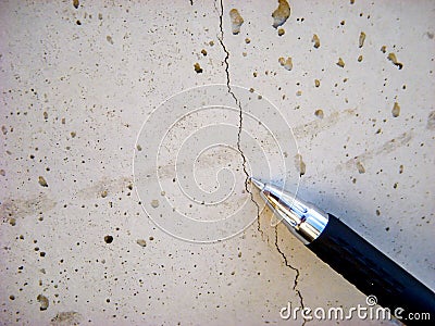 Shallow hairline crack in fresh concrete caused by shrinkage during curing. Pen used for reference. Stock Photo