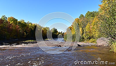 Shallow running waterfall lined with trees on a fall aftermoon Stock Photo