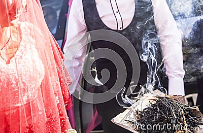 Shamanic tradition for good luck in rural Turkey. Incense of herb sticks smokes goes to young couples in a wedding ceremony Stock Photo