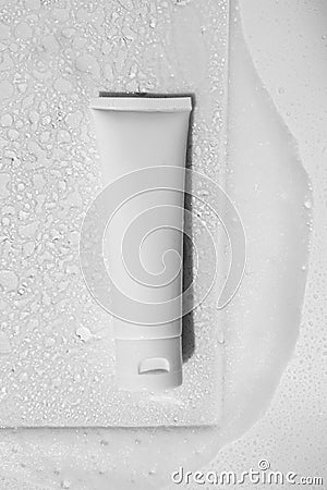 Shampoo, hair conditioner, hand cream lotion or facial cleanser in white plastic tube on glass with water drops, gentle soap foam Stock Photo