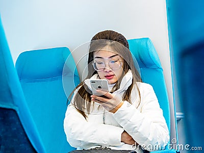 SHANGHAI, CHINA 13 MARCH 2019 - A young Chinese woman uses an Apple iphone on the Maglev train heading to Pudong International Editorial Stock Photo