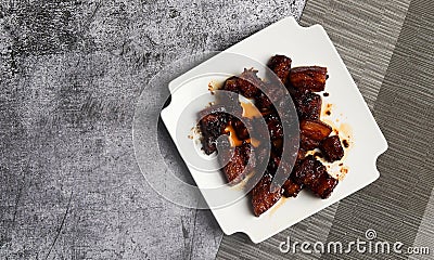 Shanghai-Style Red Braised Pork Belly or Hong Shao Rou on a white square plate on a dark background Stock Photo