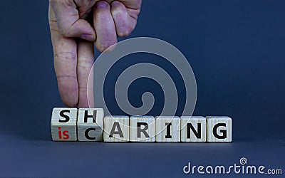 Sharing is caring symbol. Businessman turns wooden cubes with words `sharing is caring`. Beautiful grey table, grey background. Stock Photo