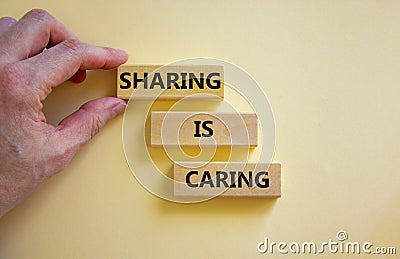 Sharing is caring symbol. Wooden blocks with words `Sharing is caring` on beautiful white background. Businessman hand. Business Stock Photo