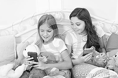 Sharing great pictures. Merry Christmas and Happy New Year greetings. Little girls use smartphone in bed. Happy little Stock Photo