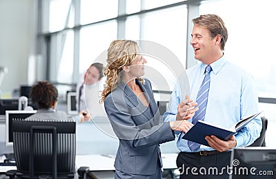 Sharing a little bit of office humour. Two happy mature business executives discussing work in the office. Stock Photo