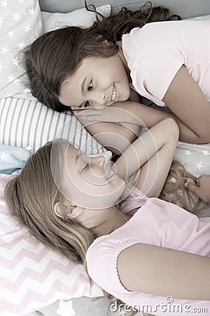 Sharing secrets. Kids relaxing on bed. Sisters preparing sleep. Nice evening. Best friends. Children friends. Charming Stock Photo