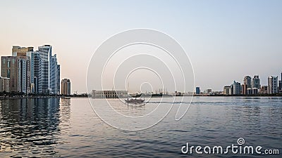 Sharjah. Summer 2016. Evening cityscape with the boat in the Persian Gulf and city architecture. Editorial Stock Photo