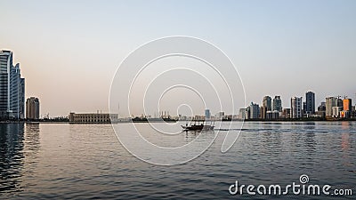 Sharjah. Summer 2016. Evening cityscape with the boat in the Persian Gulf and city architecture. Editorial Stock Photo