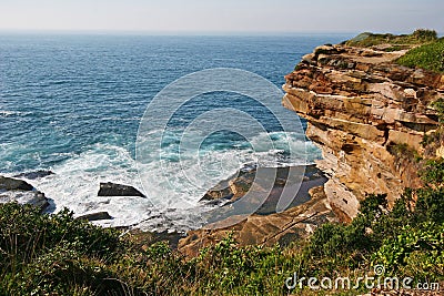 Waterfront lookout on hill with idyllic and amazing seaside landscape of bluff with shrubs, jagged coast with rocks, ocean horizon Stock Photo