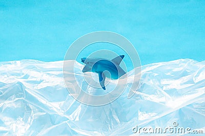 A shark toy model trapped in white plastic bag on blue background. Stock Photo