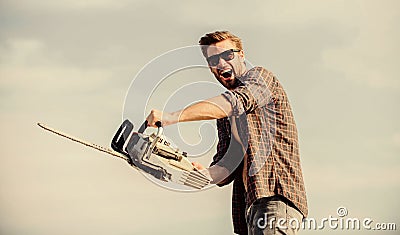 Sharp blade. Dangerous job. Feeling manly. Powerful chainsaw. Handsome man with chainsaw blue sky background. Gardener Stock Photo
