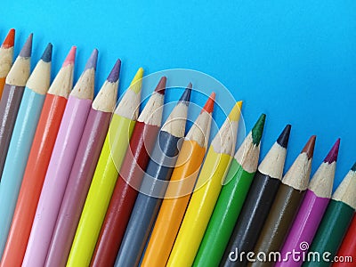 Sharp colorful pencil crayons lined up on a blue background Stock Photo