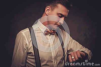 Sharp dressed man wearing bow tie looking at wristwatch Stock Photo