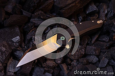 A sharp pocket knife lies at an angle on the coals Stock Photo