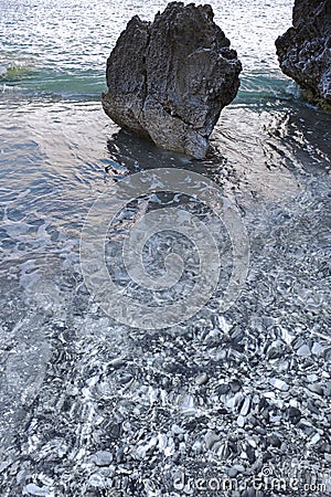 Sharp rocks on the foreshore of a pebbly beach. Shore. Stock Photo