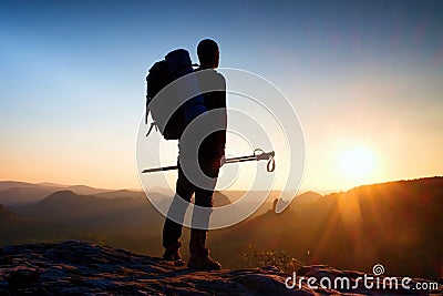 Sharp silhouette of a tall man on the top of the mountain with sun in the frame. Tourist guide in mountains Stock Photo
