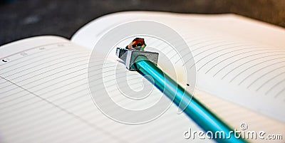 Sharpened pencil lies on a notebook, top view. Black background. Pencil planer. Close-up Stock Photo
