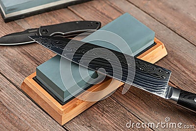 Sharpening a Japanese Gyuto knife and a jackknife with a whetstone Stock Photo