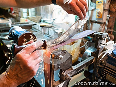 Sharpening Khukur knife on grinding machine Stock Photo