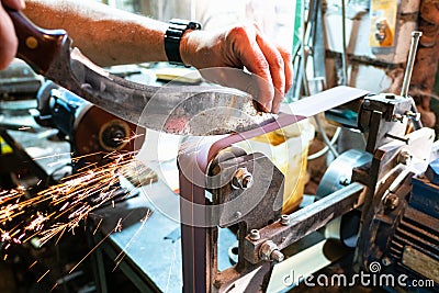 Sharpening Kukri knife on grinding machine Stock Photo