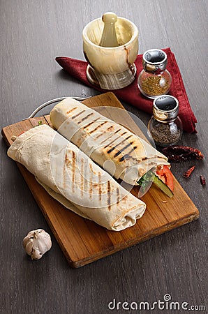 Shaurma chicken roll in a pita with fresh vegetables and cream sauce composition on wooden background Stock Photo