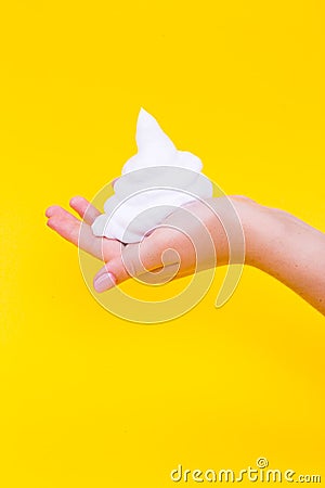 Shaving foam on a hand on a yellow background. Stock Photo