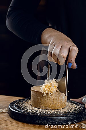 Shaving tete de moine cheese using girolle knife. Monks head. Variety of Swiss semi-hard cheese made from cows milk Stock Photo